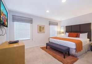 Ein Schlafzimmer mit einem Bett, Nachttischen, einer Bank und einem Fernseher.