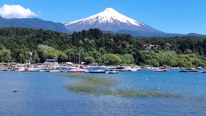 A coastal area with a mountain in the background, boats docked along the shore, and a clear sky. - A warm and cozy apartment located in a peaceful, natural, and relaxed setting (Araucanía)