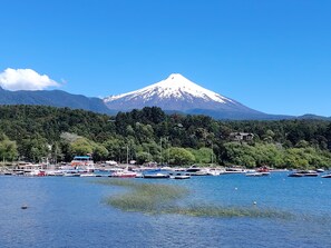 A coastal area with a mountain in the background, boats docked along the shore, and a clear sky. - A warm and cozy apartment located in a peaceful, natural, and relaxed setting (Araucanía)