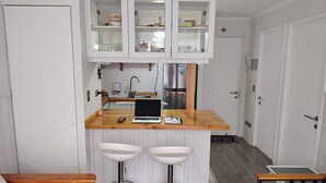 Una cocina compacta con isla integrada, dos taburetes de bar y un ordenador portátil sobre la encimera.