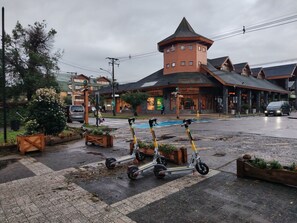 Ein Gebäude mit einem markanten Turm und einer gepflasterten Fläche mit abgestellten Elektro-Rollern.
