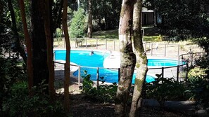 A swimming pool surrounded by trees and a fenced area. - A warm and cozy apartment located in a peaceful, natural, and relaxed setting (Araucanía)