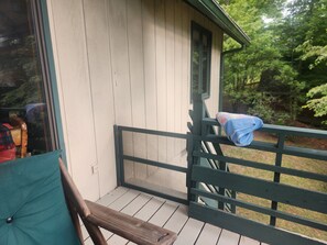 A wooden deck with a bench and a window overlooking a garden. - Classic Lakefront Cabin • Cool Mountain Vibes • 12 Mins to Cashiers (Glenville)