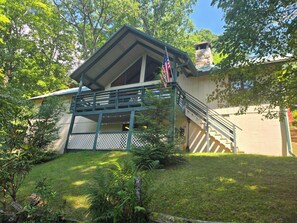 A two-story building with a balcony, a flag, and a staircase leading to the upper level. - Classic Lakefront Cabin • Cool Mountain Vibes • 12 Mins to Cashiers (Glenville)