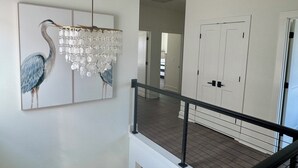 Um corredor com um candelabro, uma porta e uma escada.