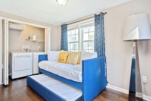 Ein kleines Schlafzimmer mit einem Bett, einer Waschmaschine und einer Lampe.