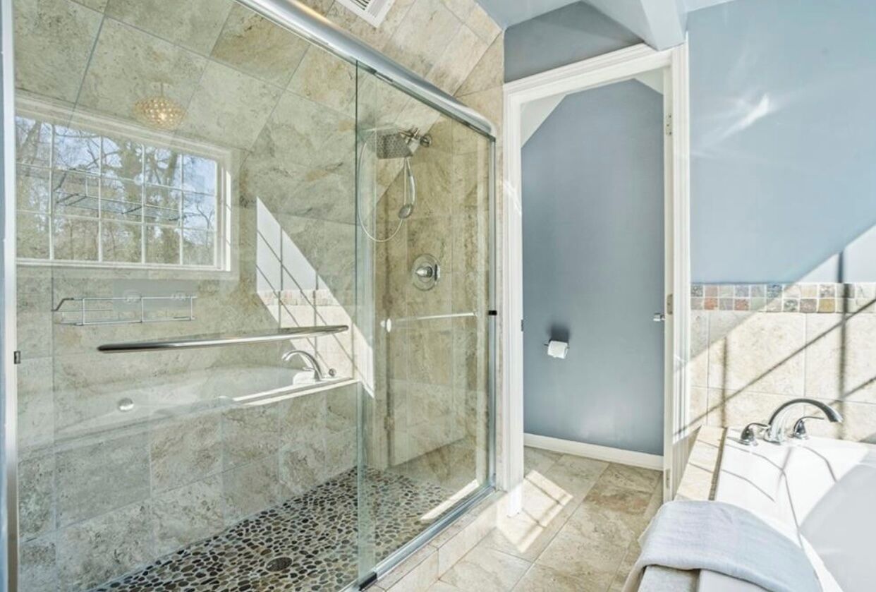 A modern bathroom with a glass-enclosed shower, a bathtub, and a toilet.