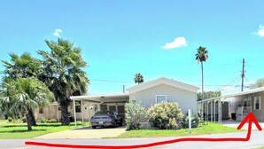 A residential area with two houses, one with a garage and a parked car, surrounded by greenery and palm trees. - Charming 2bedroom house in Mission , a few minutes to Shary Rd and La Plaza Mall (Mission)