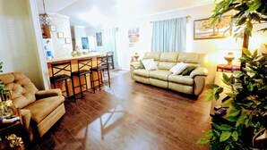 A living room with a sofa, a dining area with a bar, and a kitchen in the background. - Charming 2bedroom house in Mission , a few minutes to Shary Rd and La Plaza Mall (Mission)