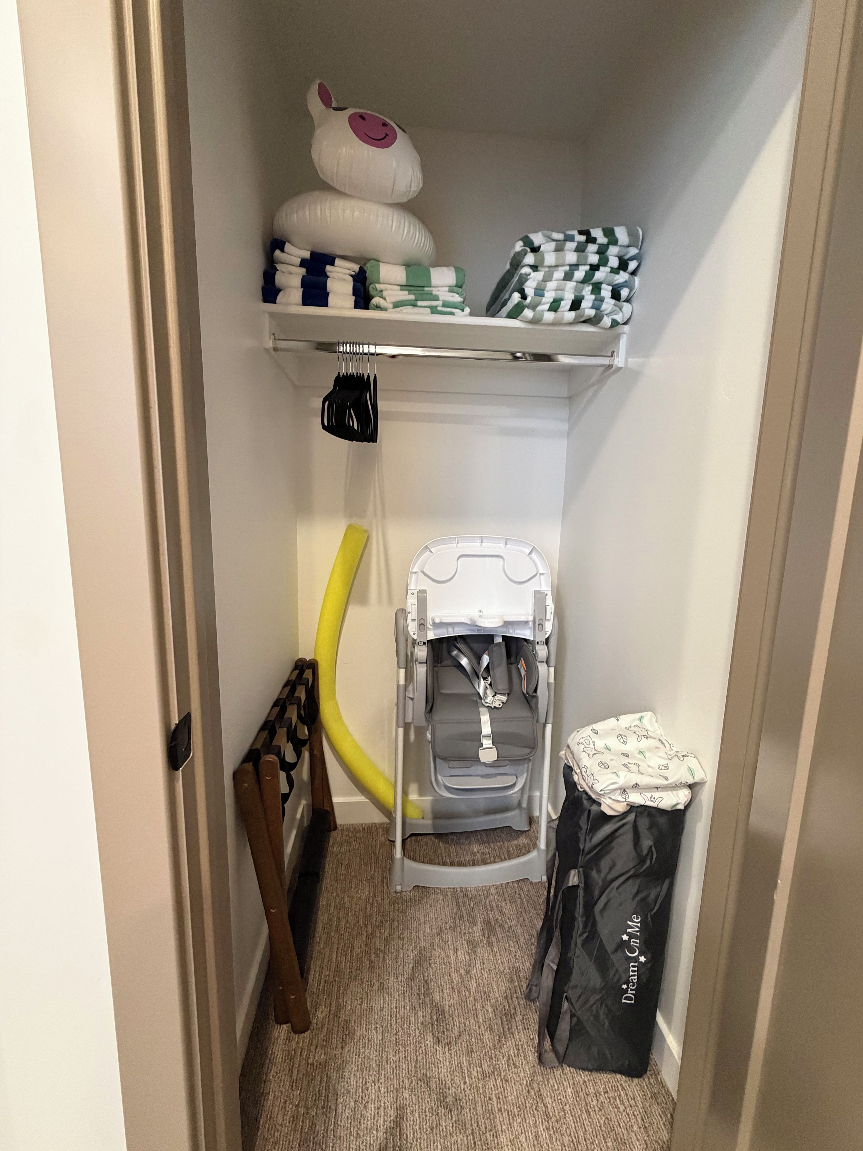 A storage closet with shelves, a stroller, a vacuum cleaner, and a trash bag.