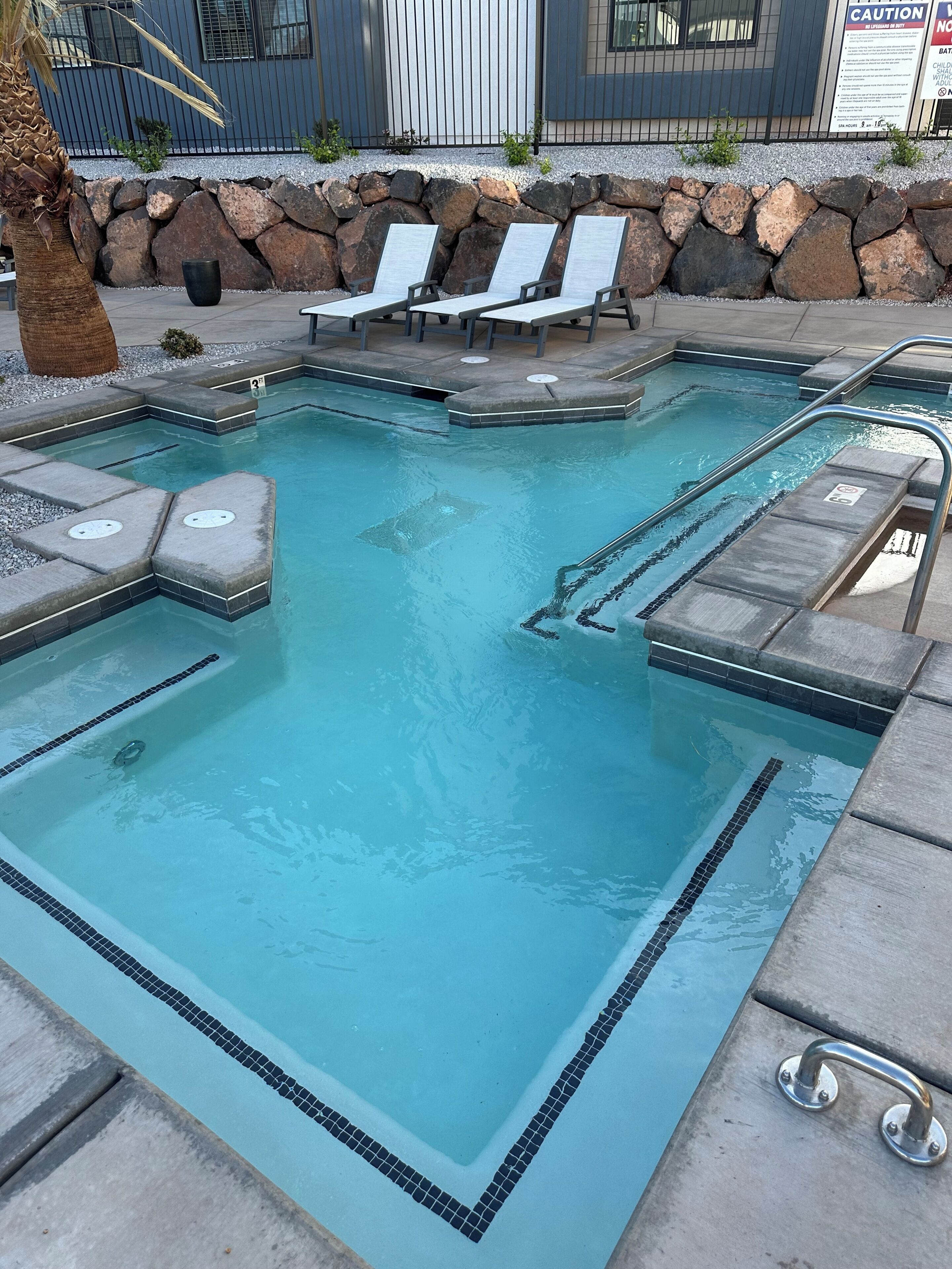 A swimming pool with lounge chairs and a stone wall.