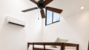 Ein Stockbett mit Holzrahmen, ein Deckenventilator, eine Klimaanlage und ein Fenster.