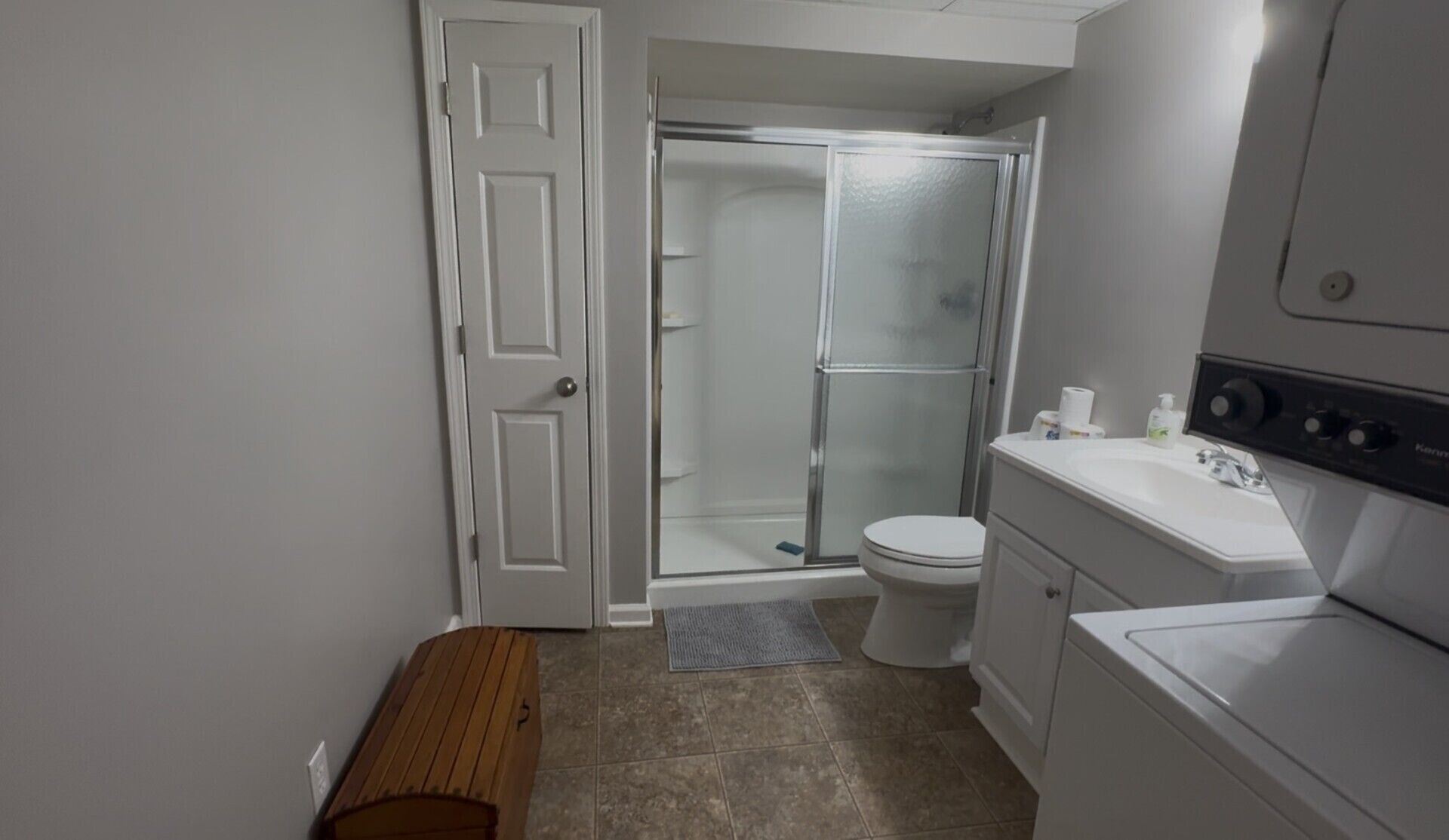 A bathroom with a toilet, shower, and a sink with a mirror.