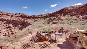 A rugged outdoor setting with a metal bench and a pile of firewood.