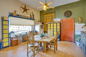 A room with a wooden dining table, chairs, a ceiling fan, and a door with a decorative pattern. - Base Camp Adventure Lodge (Moab)