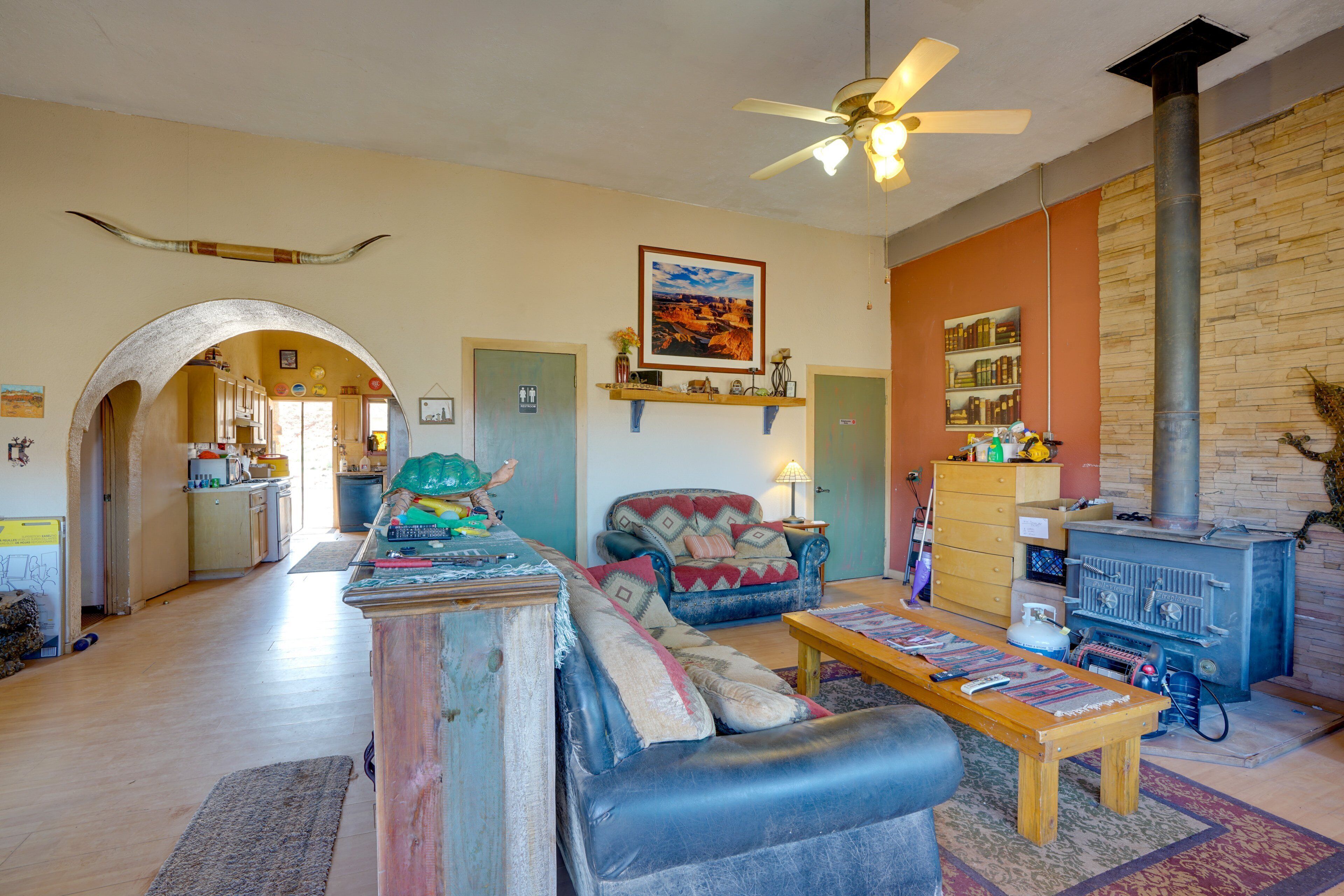 A spacious living room with a fireplace, a sofa, a coffee table, and a kitchen area visible through an archway.