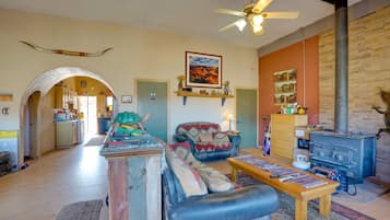 A spacious living room with a fireplace, a sofa, a coffee table, and a kitchen area visible through an archway.