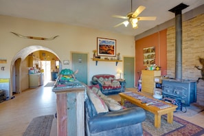 A spacious living room with a fireplace, a sofa, a coffee table, and a kitchen area visible through an archway.