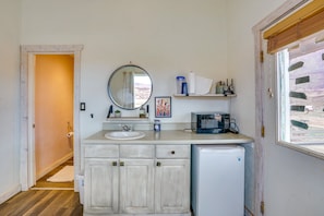 A compact bathroom with a sink, mirror, and a microwave.