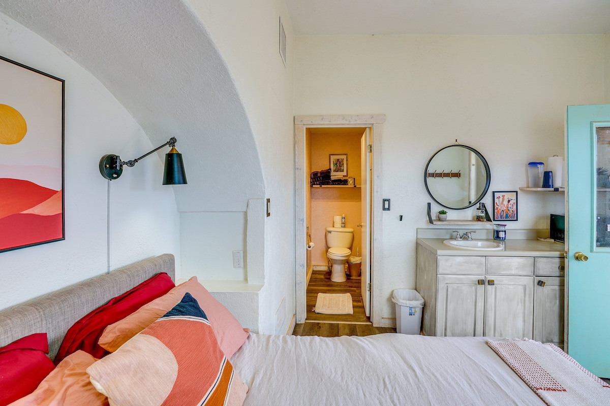 A bedroom with a bed, a nightstand, a wall-mounted lamp, and a painting.