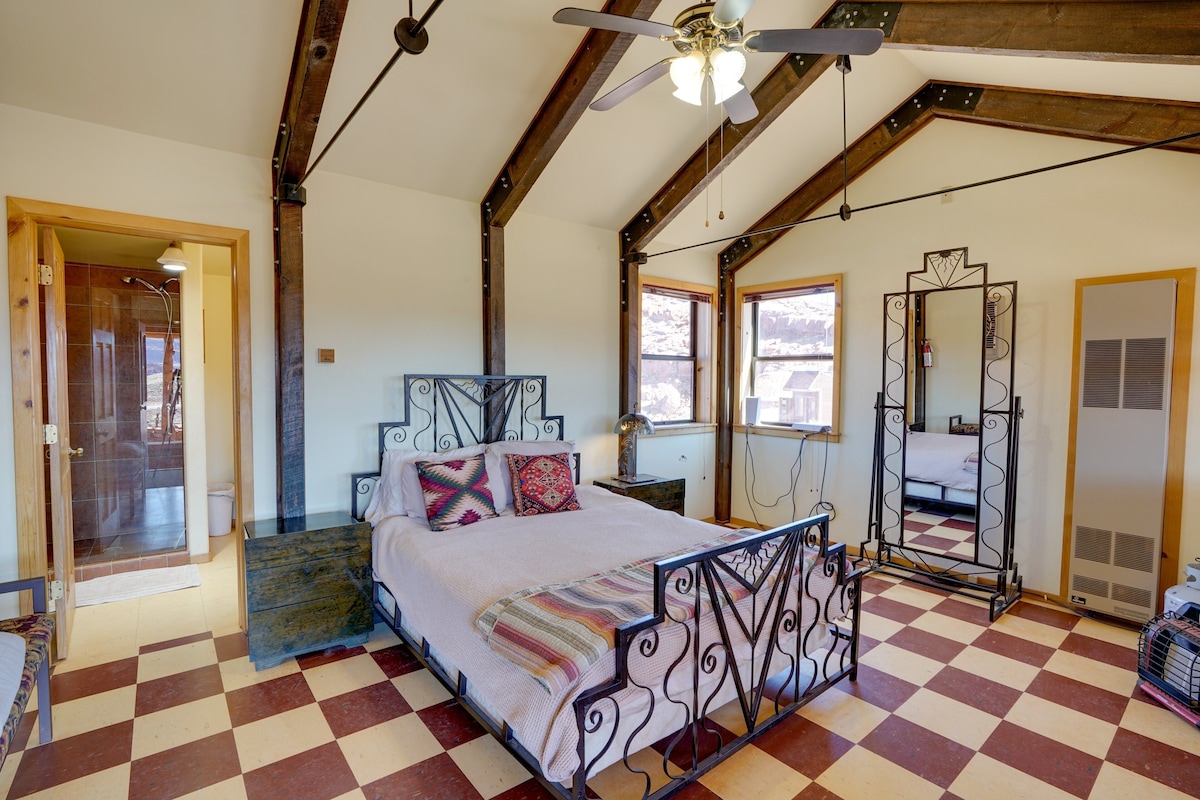 A bedroom with a checkered floor, a bed with a metal frame, a ceiling fan, and a large mirror.