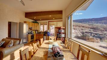 A spacious living area with a dining table, a sofa, and a view of a canyon.