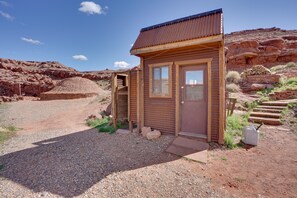 A small wooden cabin with a corrugated metal roof, a wooden door, and a window. - Base Camp Adventure Lodge (Moab)