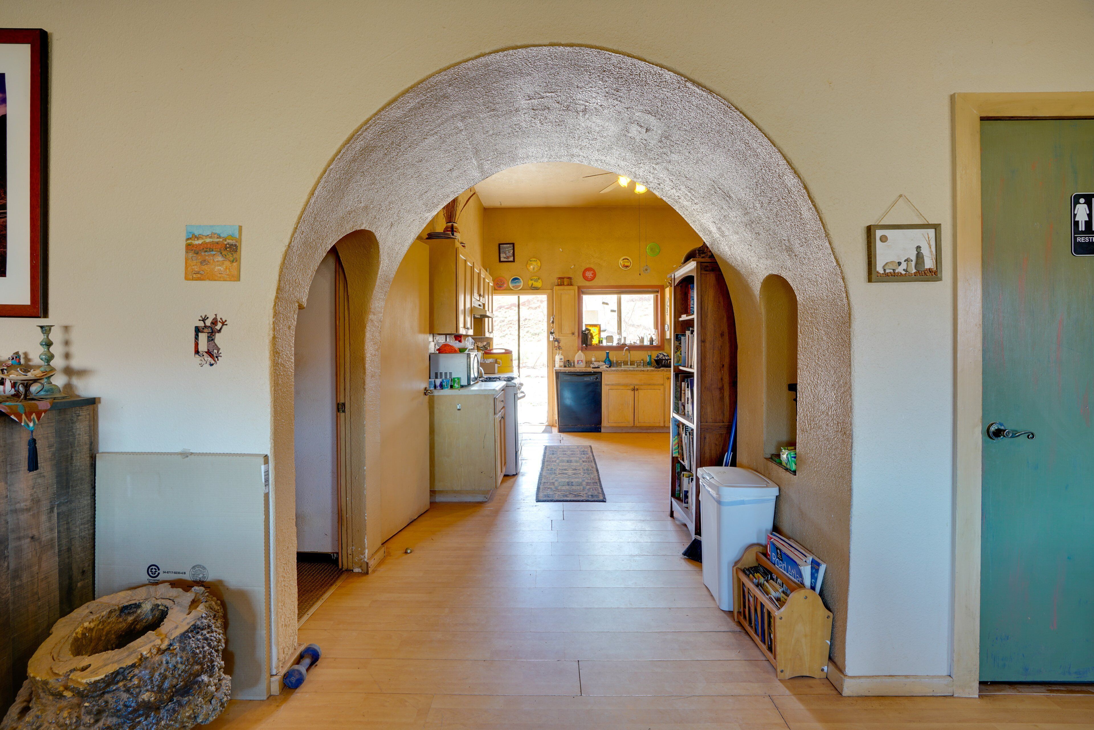 A hallway with an arched doorway leading to a kitchen area.