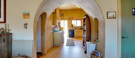 A hallway with an arched doorway leading to a kitchen area.