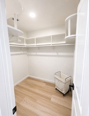 A white closet with wooden flooring, white walls, and a metal storage cart. - Blue Horizon • 5 minutes to Launch Ramp + Lake Views + Game Room! (Lake Havasu City)