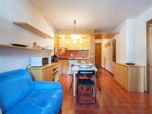 A compact kitchen with a dining area, a microwave, and a blue sofa. - Ai Pascoli by Interhome (Madesimo)