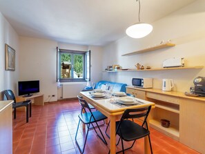 Un espace de vie compact comprenant un coin repas, une kitchenette et un téléviseur.