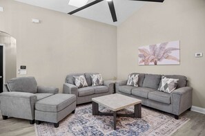 Ein modernes Wohnzimmer mit grauen Sofas, einem Couchtisch und einem gemusterten Teppich.