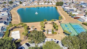 Ein Wohngebiet mit einem großen Teich, einem Tennisplatz und mehreren Häusern mit Solaranlagen.