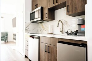 A modern kitchen with wooden cabinets, a built-in microwave, and a coffee machine. - New Vineyard Cottage in Niagara Wine Country | 1BR | Pet Friendly (Lincoln)