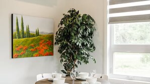 Un coin repas avec une table ronde, des chaises blanches et une plante en pot.