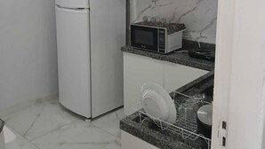 A compact kitchen with white cabinets, a built-in microwave, and a dish rack. - House 5 minutes from the Mozambique dunes trail (Florianópolis)