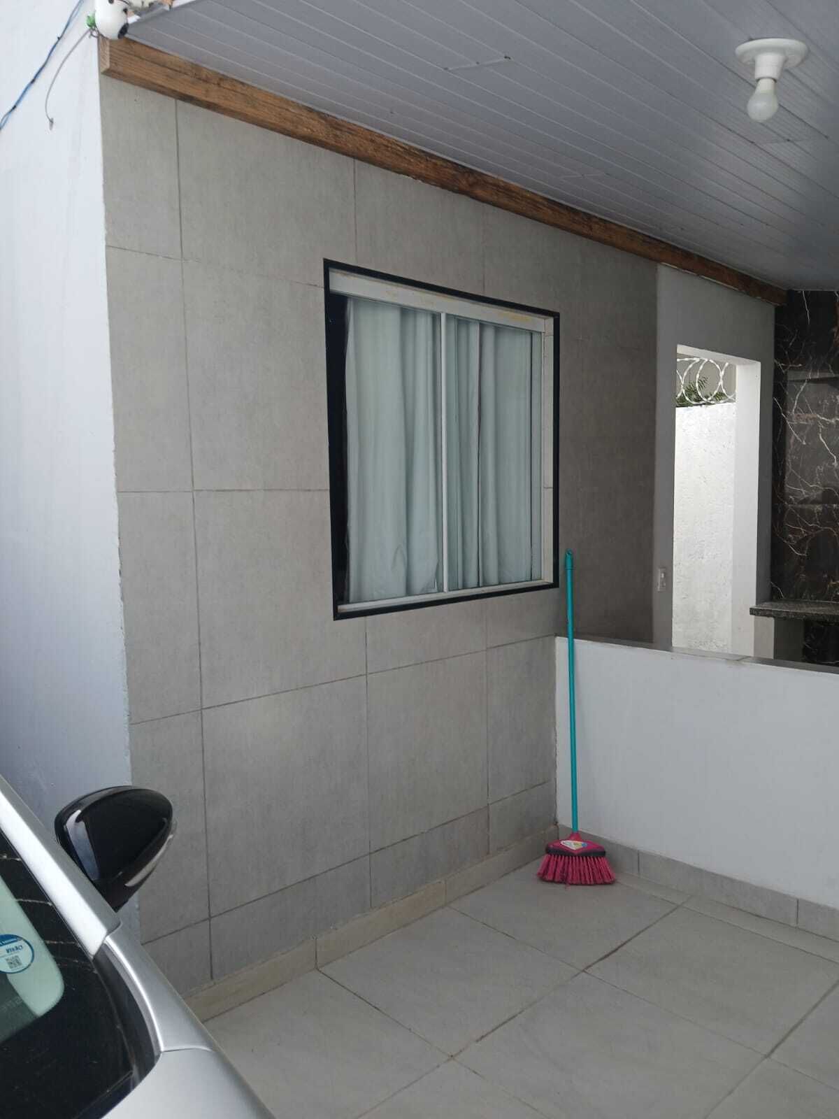 A room with a window, a mop, and a car parked outside.