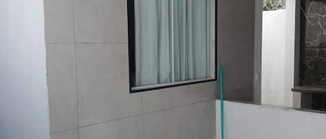 A room with a window, a mop, and a car parked outside.