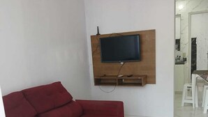 A living room with a red sofa, a mounted TV, and a red rug. - House 5 minutes from the Mozambique dunes trail (Florianópolis)