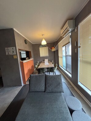 A compact living space with a sofa, dining table, and chairs. - Straight from KIX! Easy Access to Kyoto & Nara / Spacious House for Families & Groups (大阪市西成区千本北)
