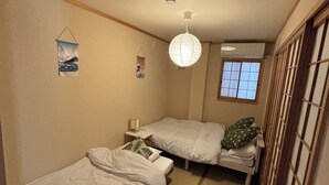 Una habitación pequeña y estrecha con dos camas individuales, una lámpara colgante y una ventana con vistas.