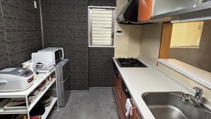 Una cocina pequeña equipada con estufa a gas, un lavamanos y un ventanal con persianas.
