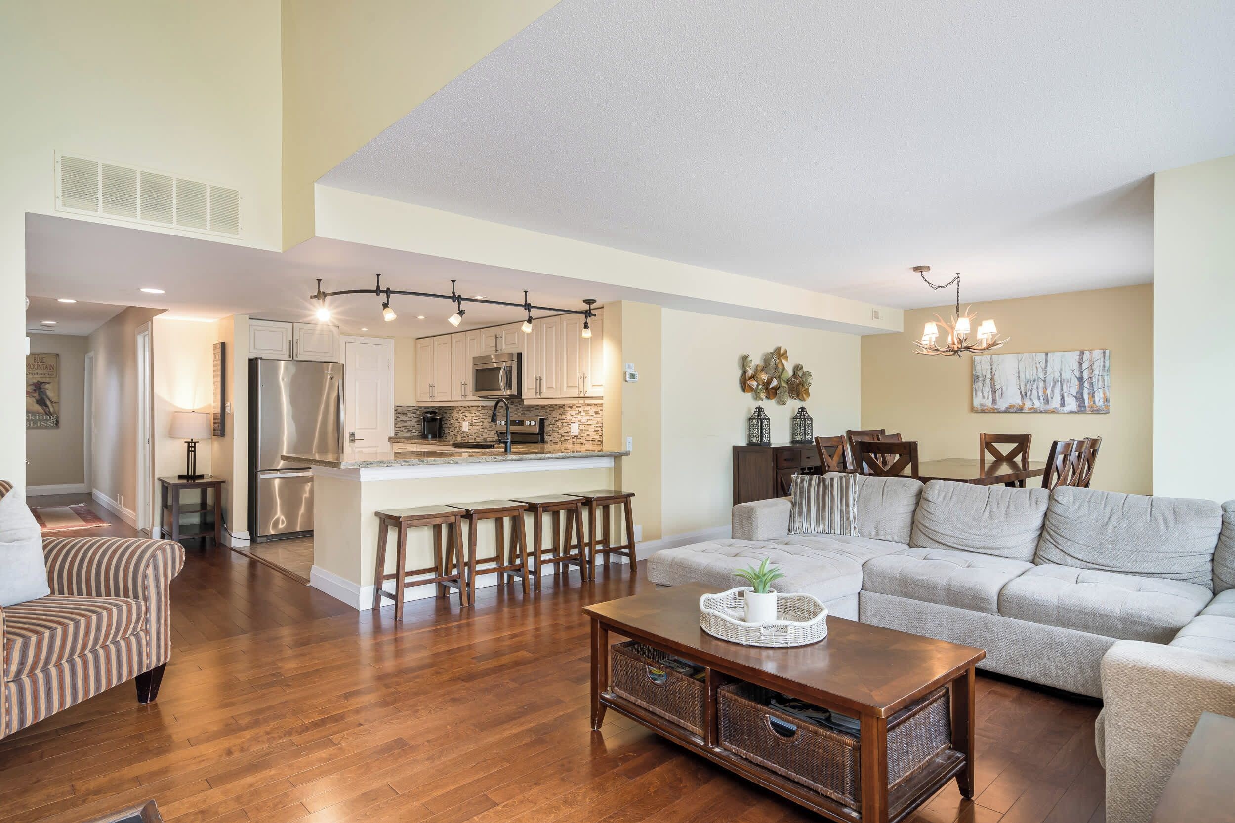 A spacious living room with a large sofa, a coffee table, and a dining area with chairs.