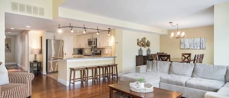 A spacious living room with a large sofa, a coffee table, and a dining area with chairs.