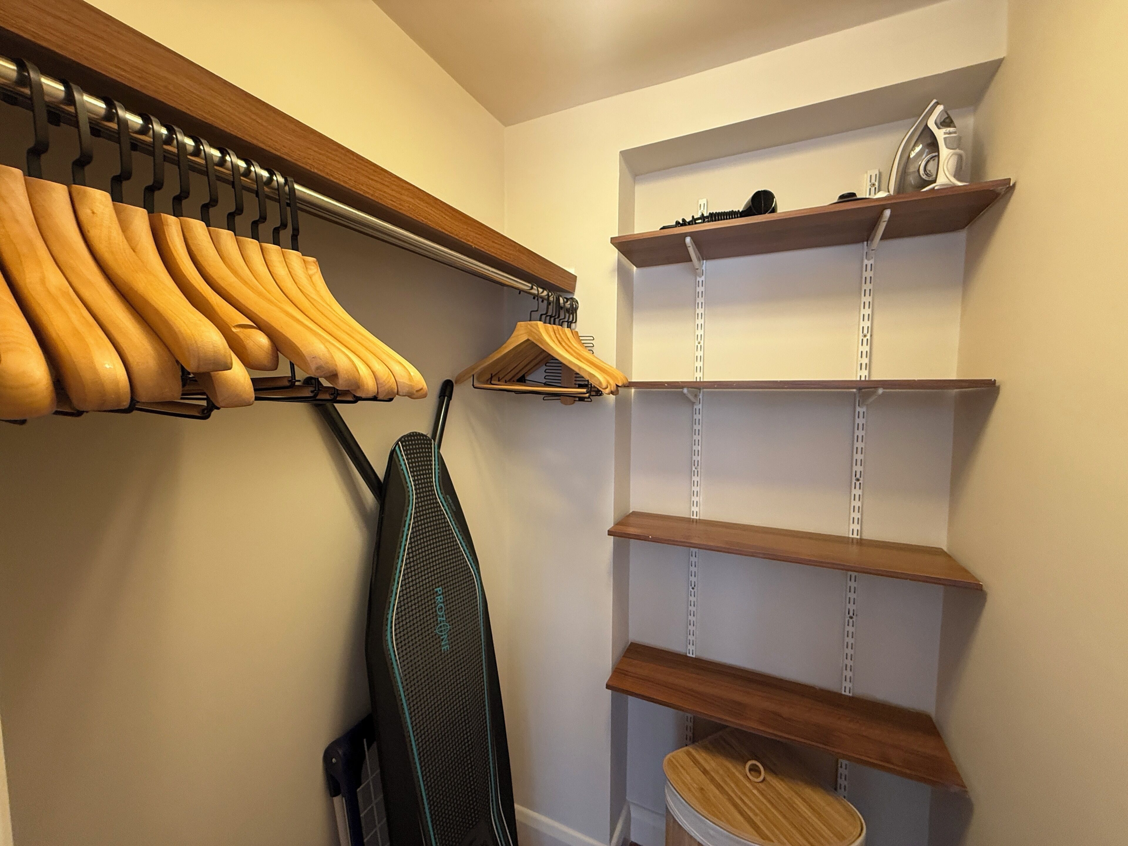 A closet with wooden shelves, a hanging rack, and a shoe rack.