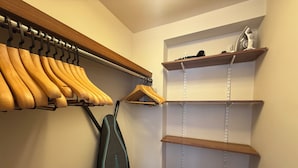Un armario con estantes de madera, una barra para colgar ropa y un zapatero.