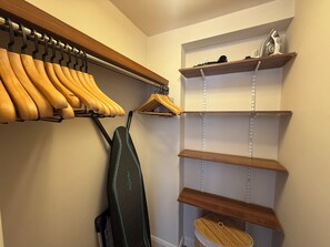 Ein Schrank mit Holzböden, einer Kleiderstange und einem Schuhregal.