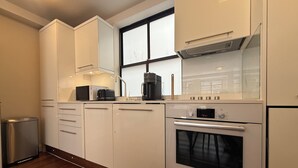 Una cocina moderna con armarios blancos, un horno Bosch y una cafetera.