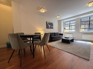 Ein modernes Wohnzimmer mit Essbereich, einer Couch, einem Couchtisch und einem Teppich.